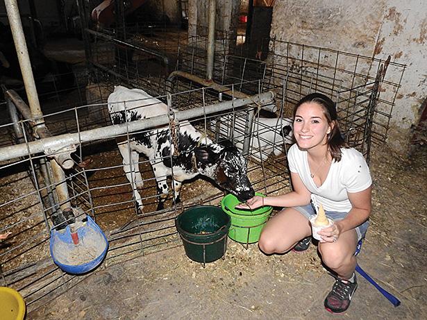 Senior healthcare management major Jen Mathiesen poses with a calf at The Lands  at Hillside Farms. 