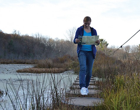 Junior health care management/pre-DPT major Arielle Kneller gazes over a map of the park while navigating through the stepping stones. The stepping stones lead over marsh lands in the middle of prime hunting grounds. 