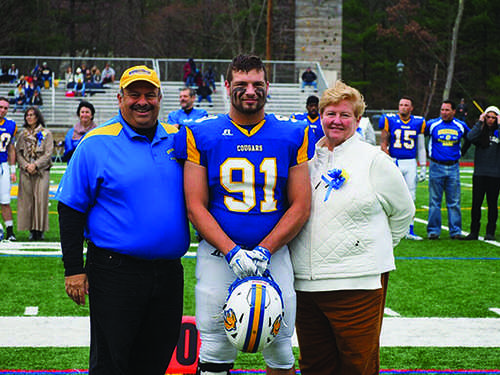 Senior defensive end Greg Zotian walks down the center of the field with his parents. 
