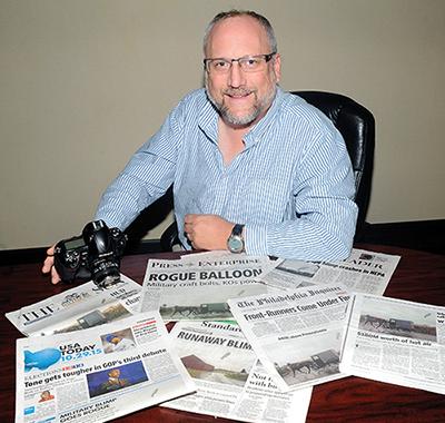 Jimmy May, adjunct professor in the communications department, took the defining photograph of the recent runaway Army balloon as it moved through Columbia County. Here he is seen with some of the newspapers that used his photograph. 