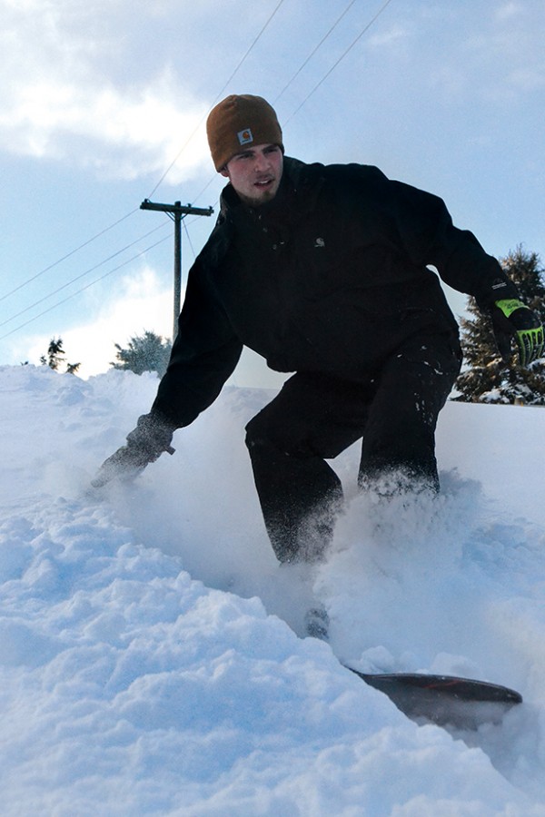 Tyler+Bartron+snowboards+down+the+hill+on+a+ranch+where+horses+are+boarded.++