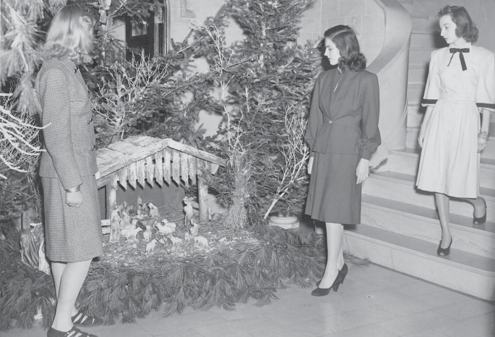 Three female students, dressed in their best attire, admire a manger scene in the Mercy Hall Foyer in 1949.