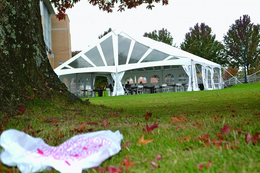 A plastic bag from the Metz Dining Hall lies on the ground near the outdoor tent eating area as teachers and students are eating their take-out food.