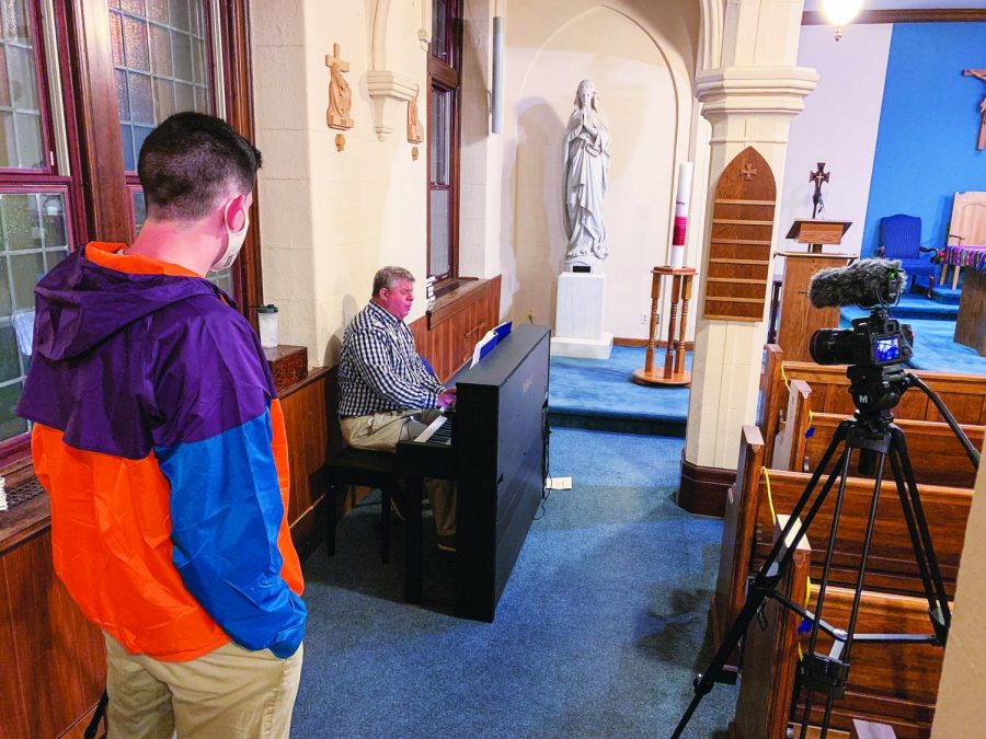 Senior Sean Gorman (left) assisting with filming of the Alumni Memorial Mass for Homecoming Weekend. Raymond Podskoch ’90 on piano playing hymns.
