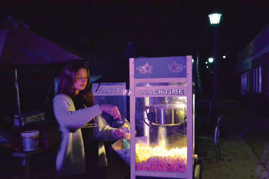 Freshman OT Major Juliana stirs and serves warm buttered popcorn in the cold evening of the fall fest.